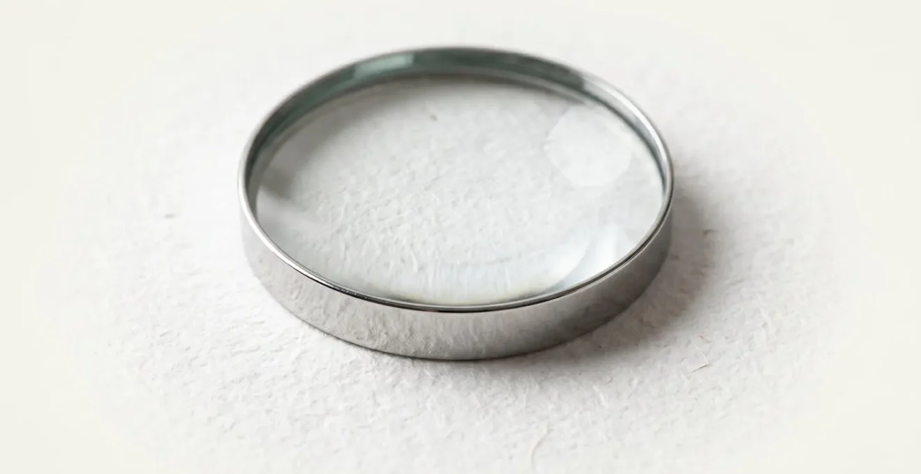 Macro close-up of magnifying glass examining textured paper surface with natural lighting